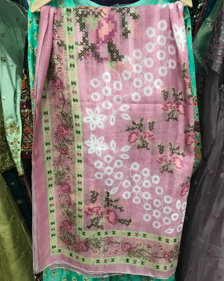 A pink embroidered dupatta or scarf with white floral motifs and green border details, displayed on a hanger in a clothing rack.